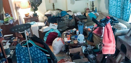 A home living room clutterd with everything you could possibly think of, it looks like the resident of the home moved every thing they own in to this room. All the things you would expect to see in a living room are not visible because of all the clutter