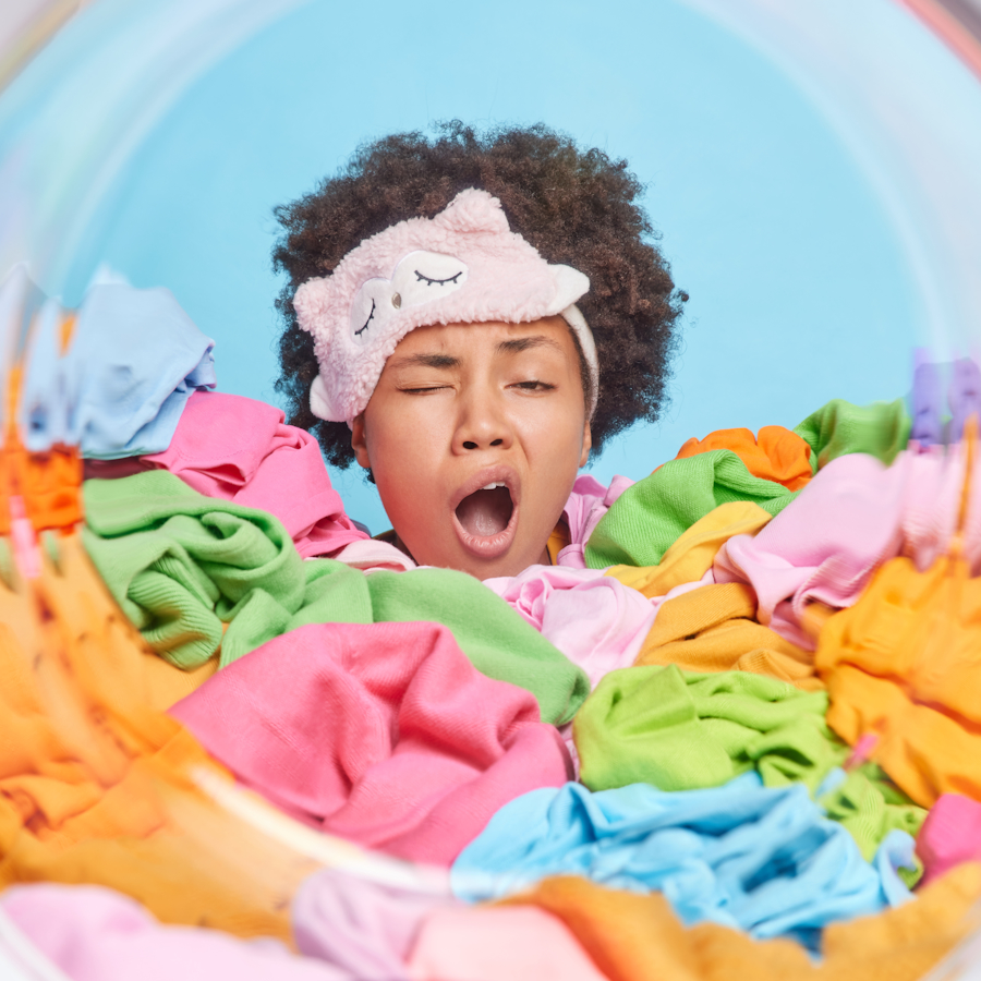 Woman yawning as she looks at laundry in a washing machine