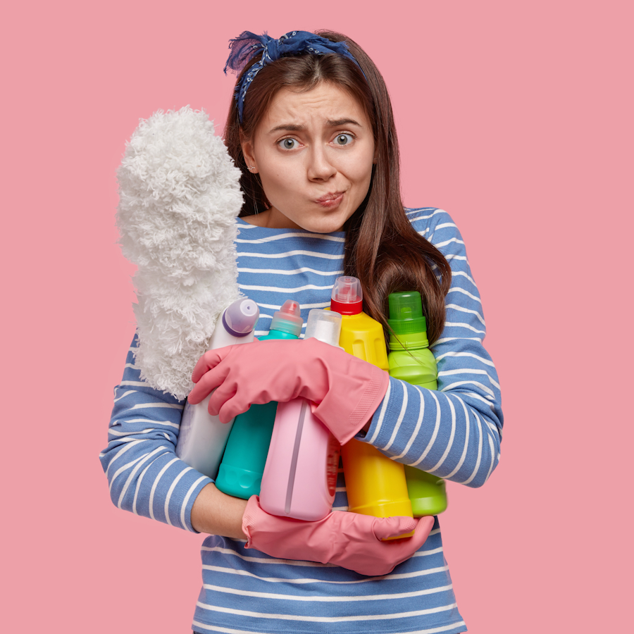 Woman holding multiple cleaning supply bottles and a mop duster